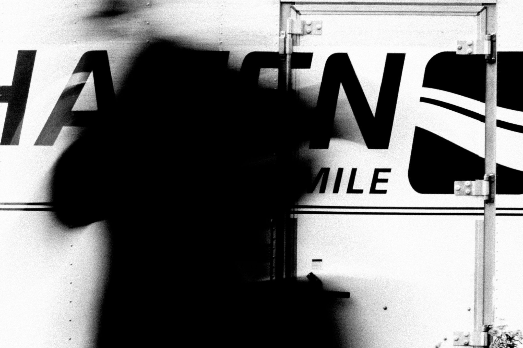 A blurred woman in front of a delivery truck shot by Jay Sennett with a Canon 60D while pulling focus.