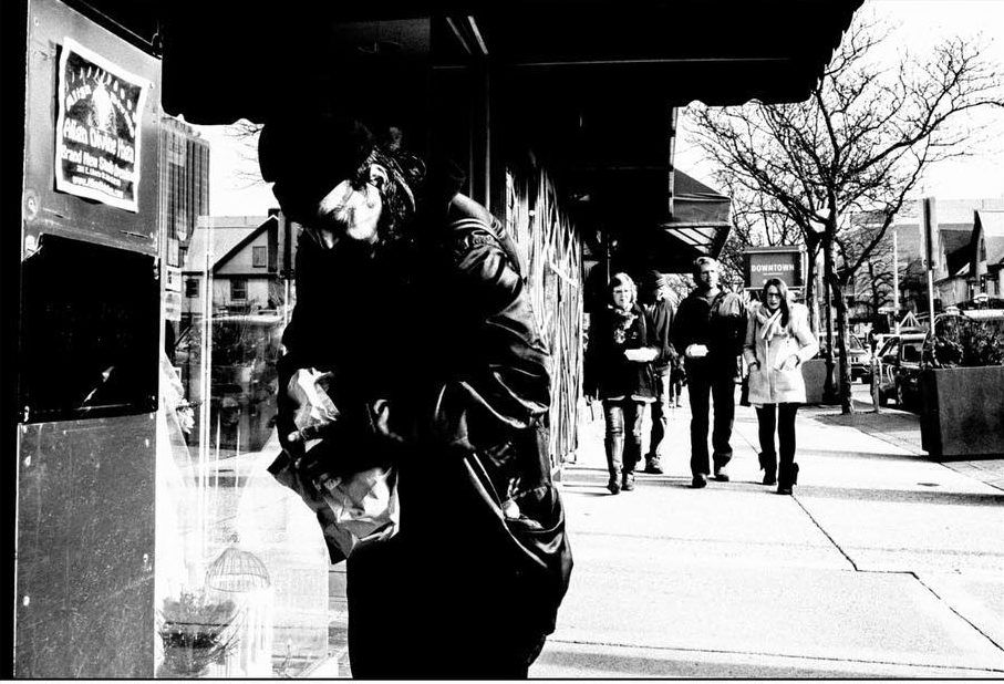 A homeless man rips open a bag filled with burgers. Shot with a Ricoh GR2 by Jay Sennett.